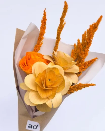 A flower bouquet with 1 fossilized stem orange rose and 2 wooden flowers wrapped in a paper.