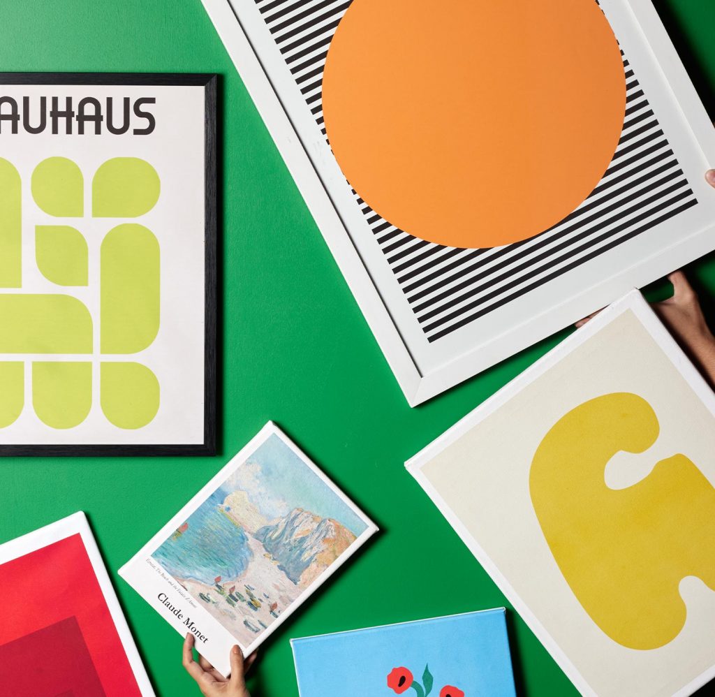 Posters and canvas prints photographed in a green background including Claude Monet inspired art and Bauhaus art