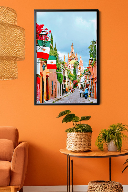An art print of the street to the Parroquia hanged on an orange walled room
