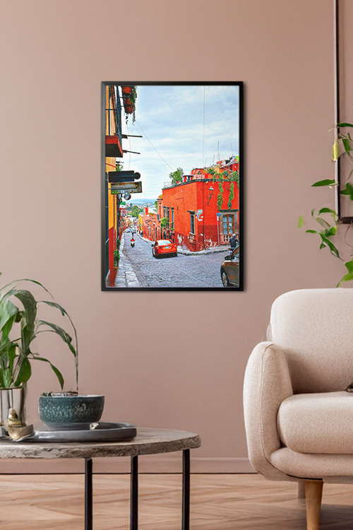 A poster print in a black frame with a photo of a red car descending on a concrete valley in Spain as a home wall decoration