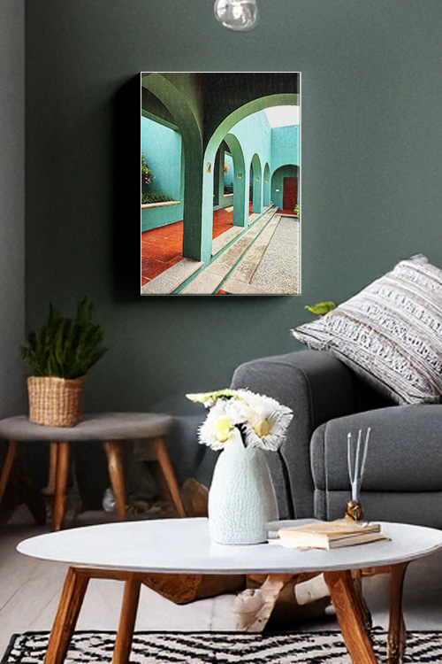 A photo canvas print displayed on a dark-colored wall showing a pathway with arches and a wall with a different hues of green